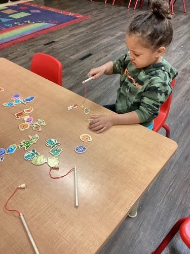 Child playing with a fishing game at a table