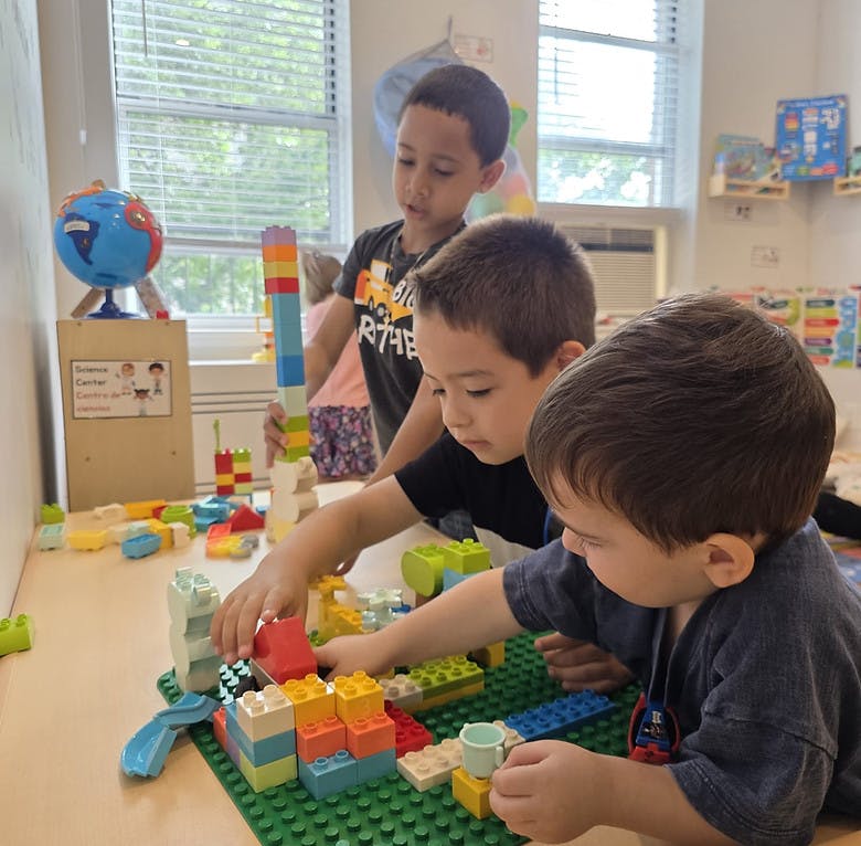 Three children building with colorful blocks on a table