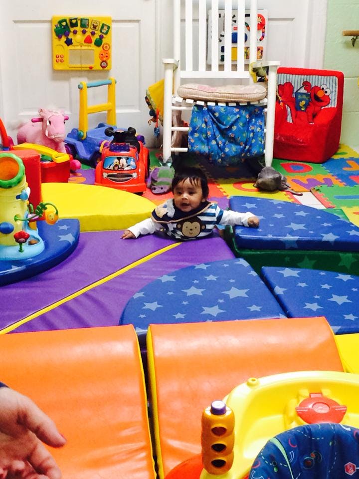 Child crawling on soft play mats in a room with toys