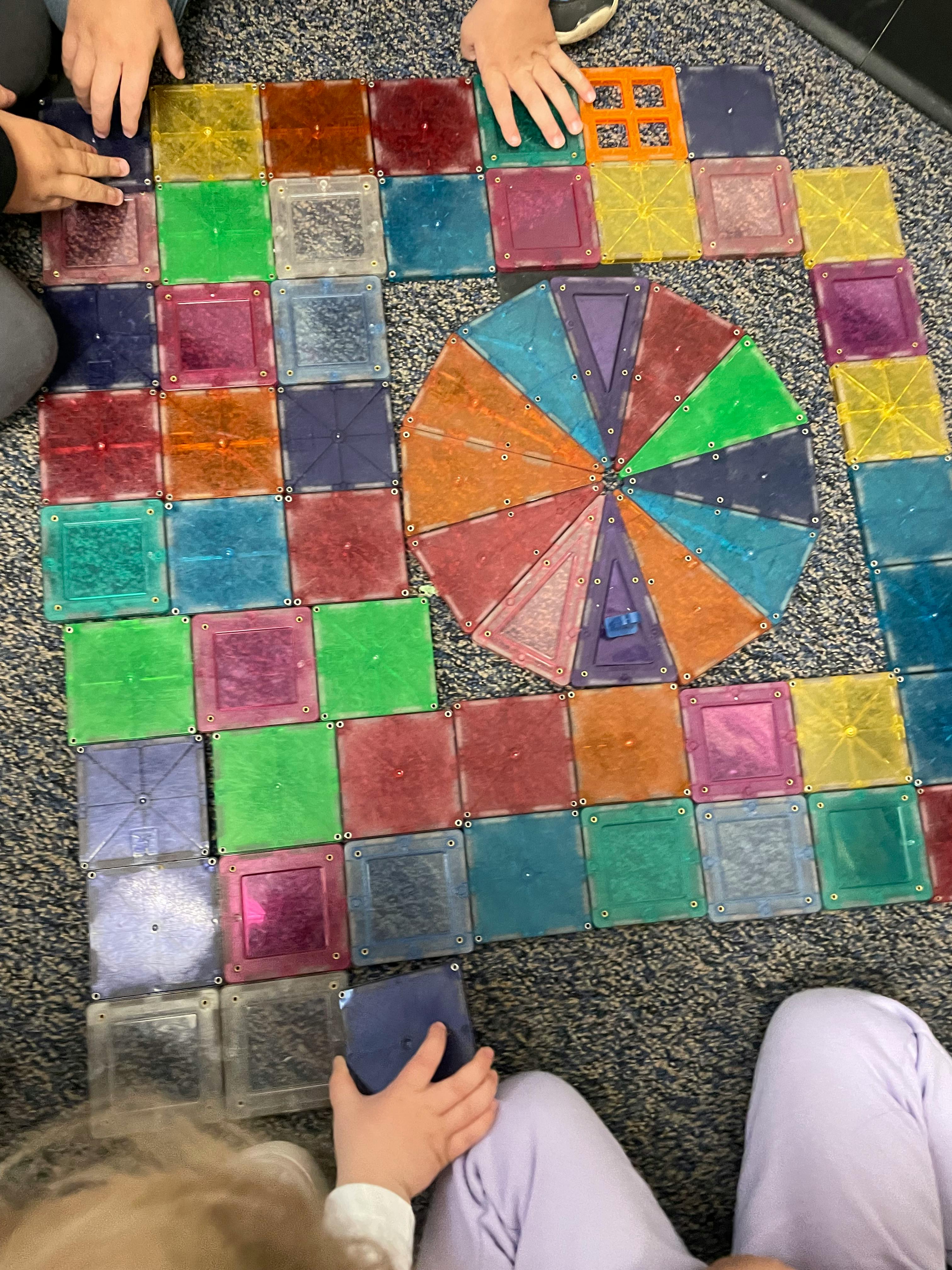 Children playing with colorful magnetic tiles on a carpet