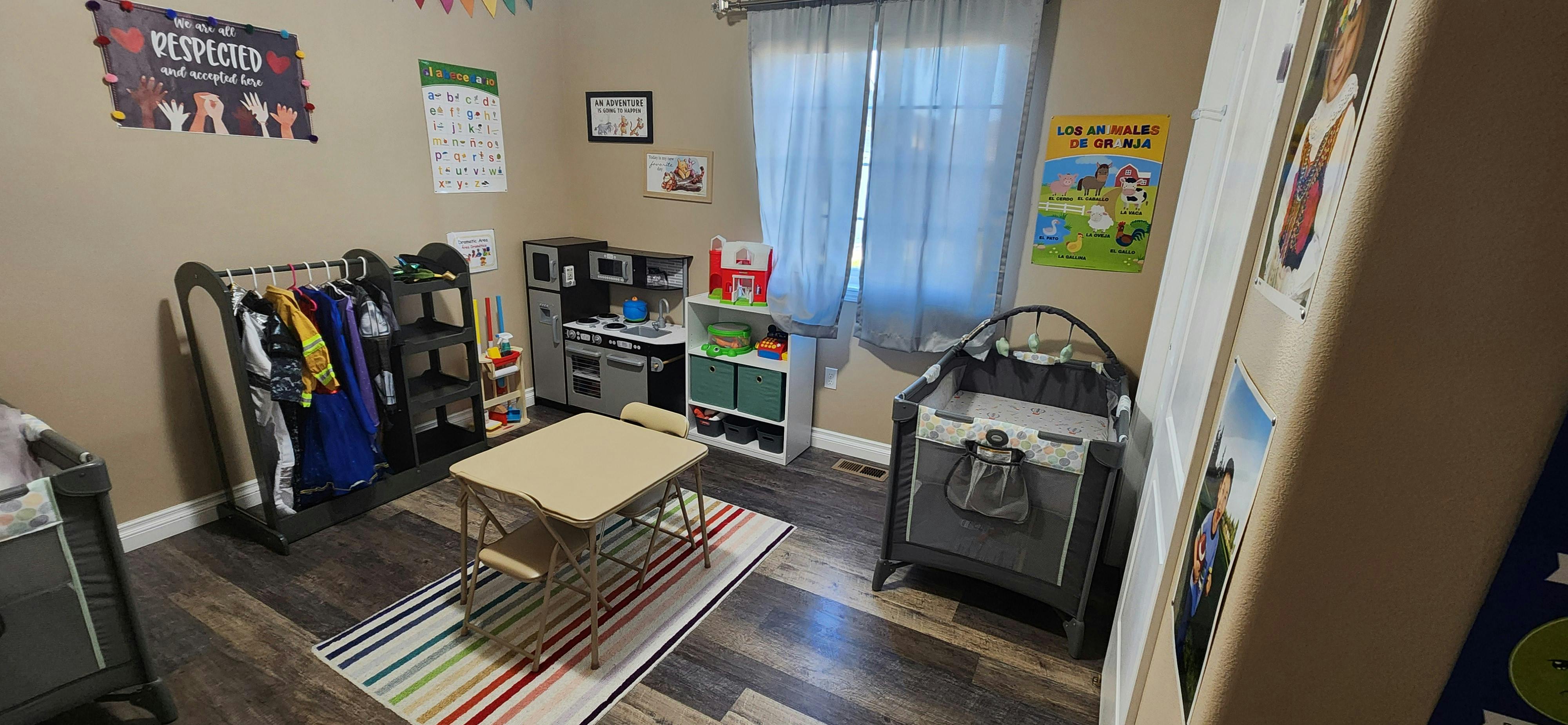 Children's play area with a small table, clothes rack, and toy kitchen