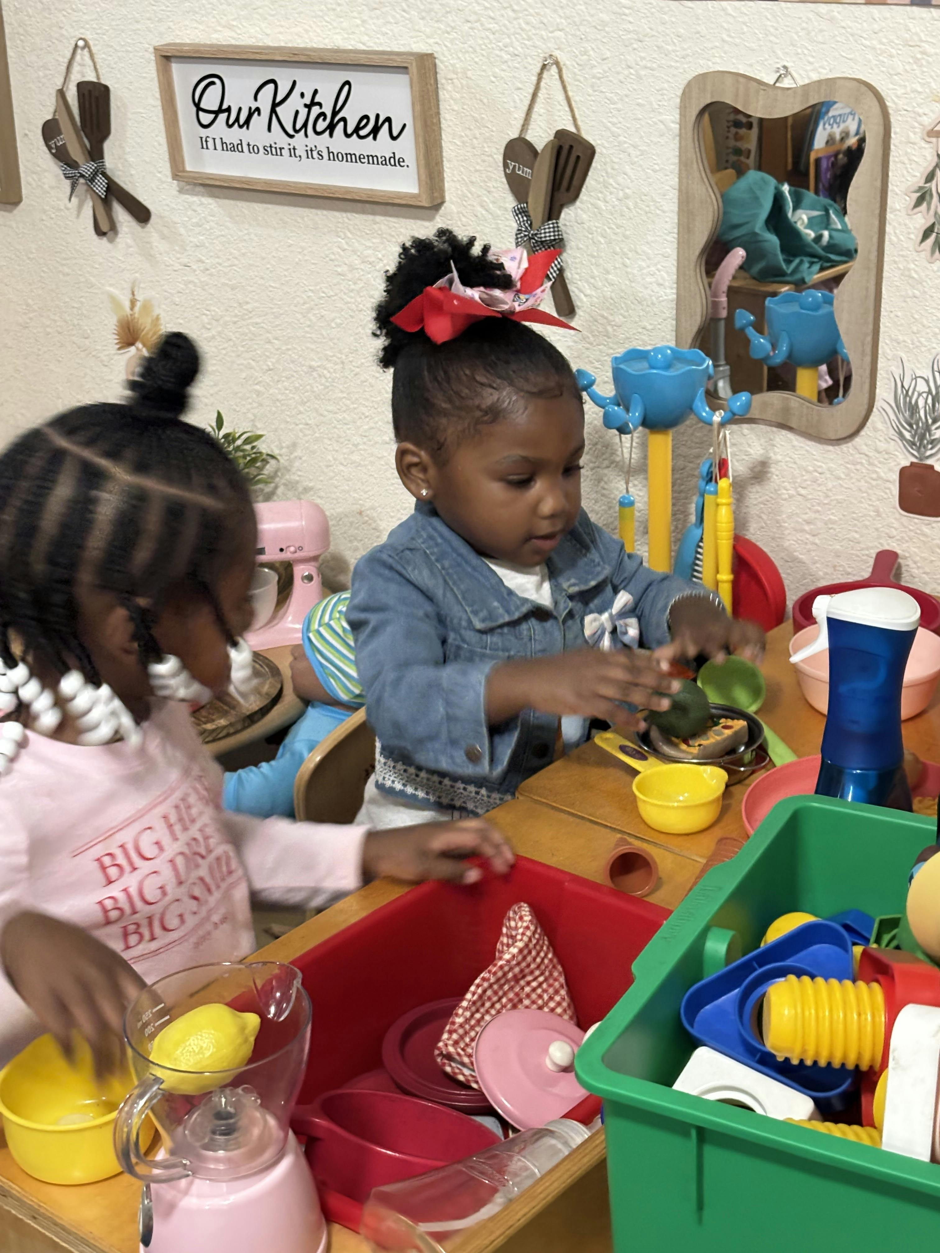 Two children playing with a toy kitchen set