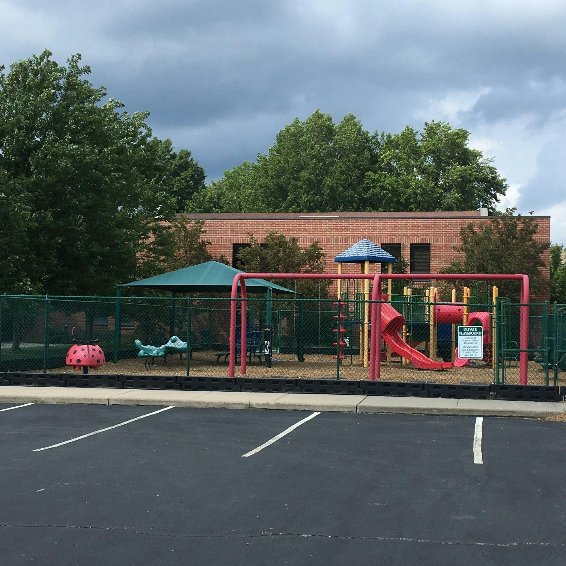 Playground with swings, slide, and spring riders behind a fence