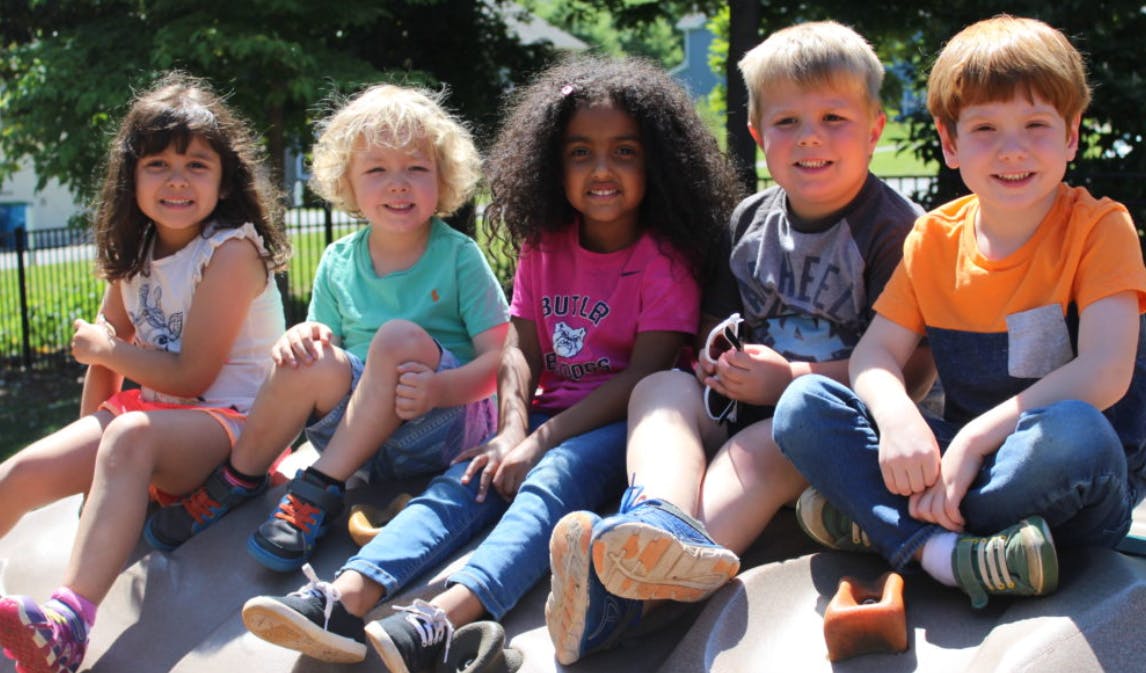 Five children sitting together outdoors