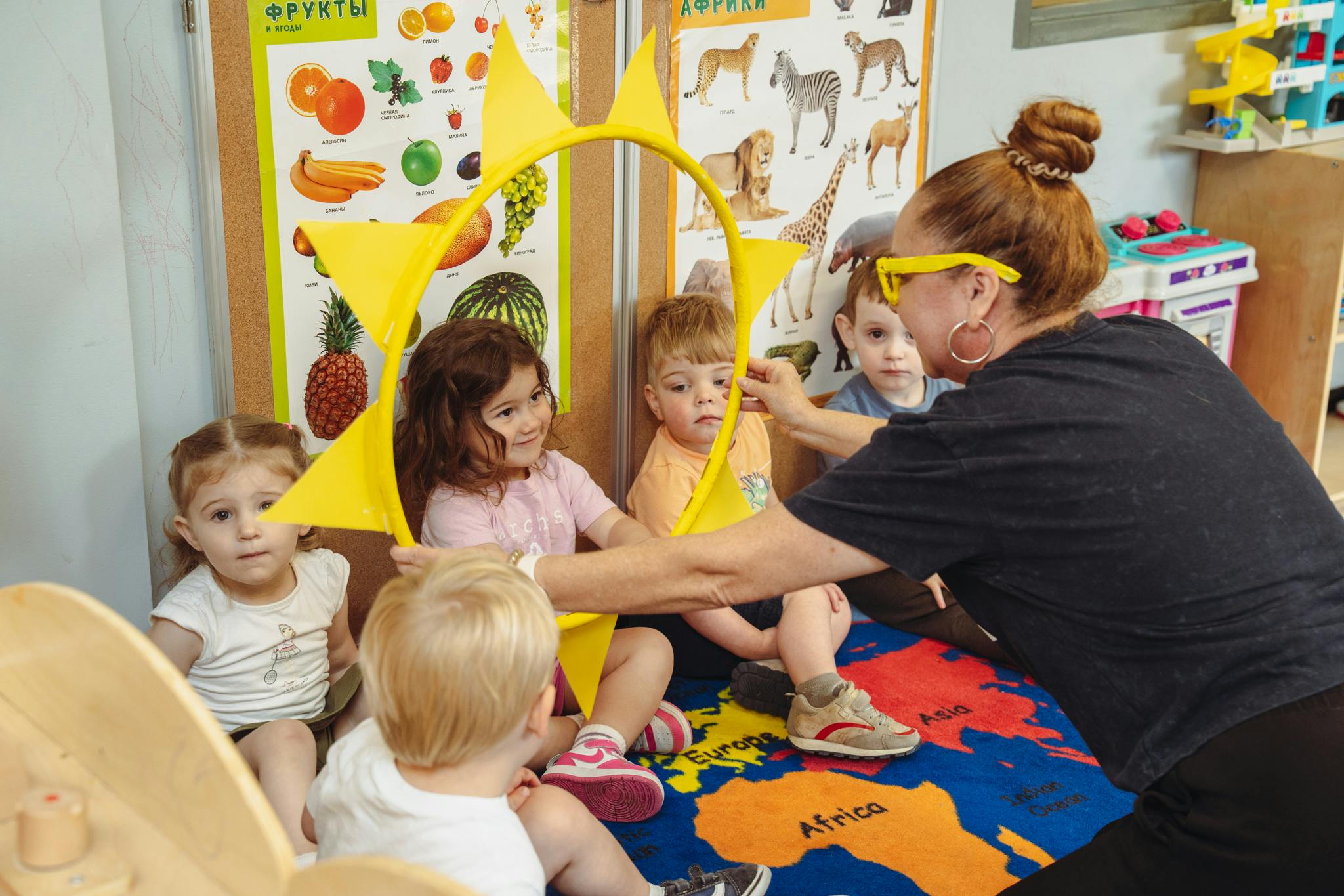 Adult and children playing with a yellow sun prop in a classroom