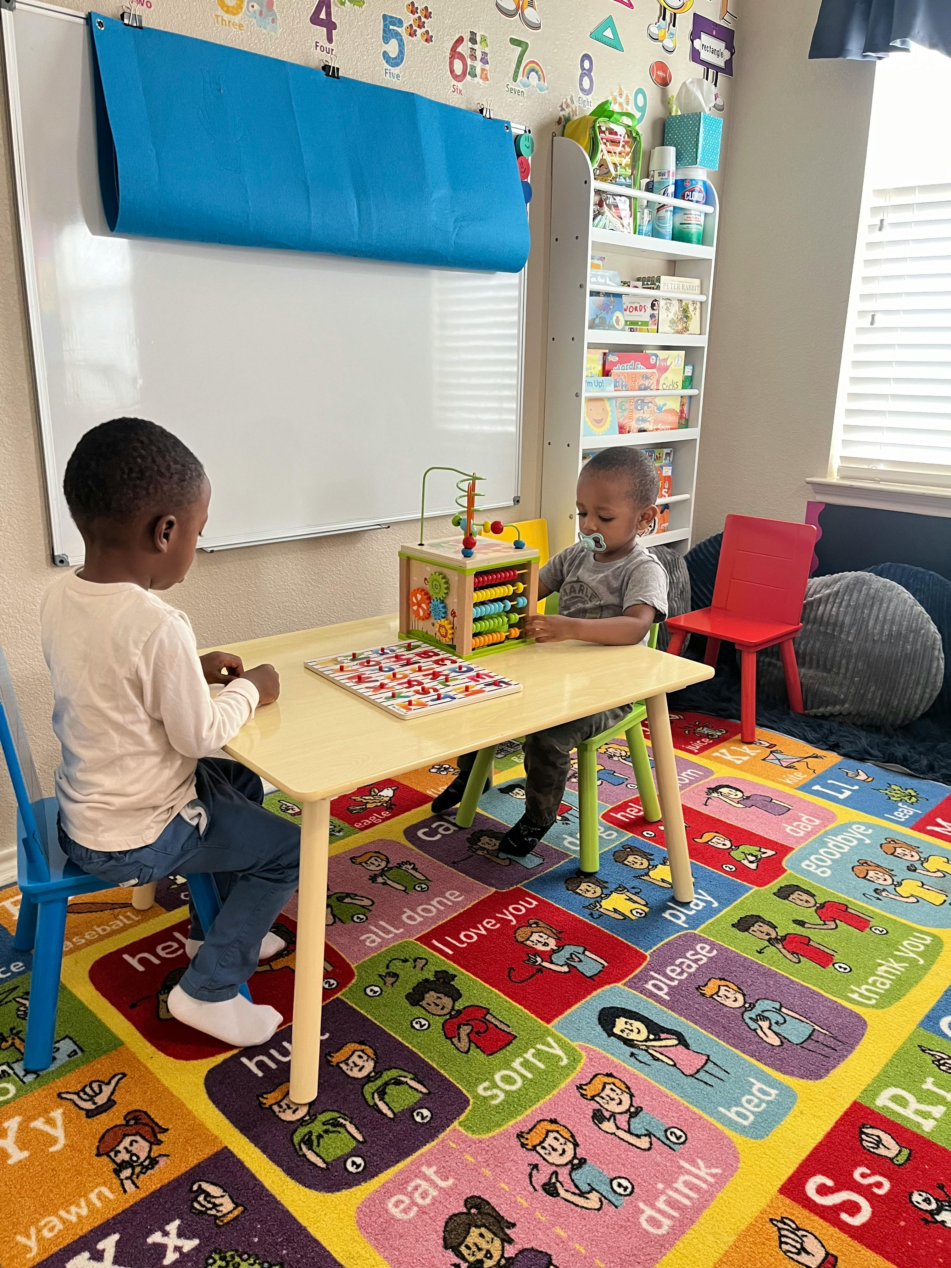 Two children playing with toys at a small table in a classroom