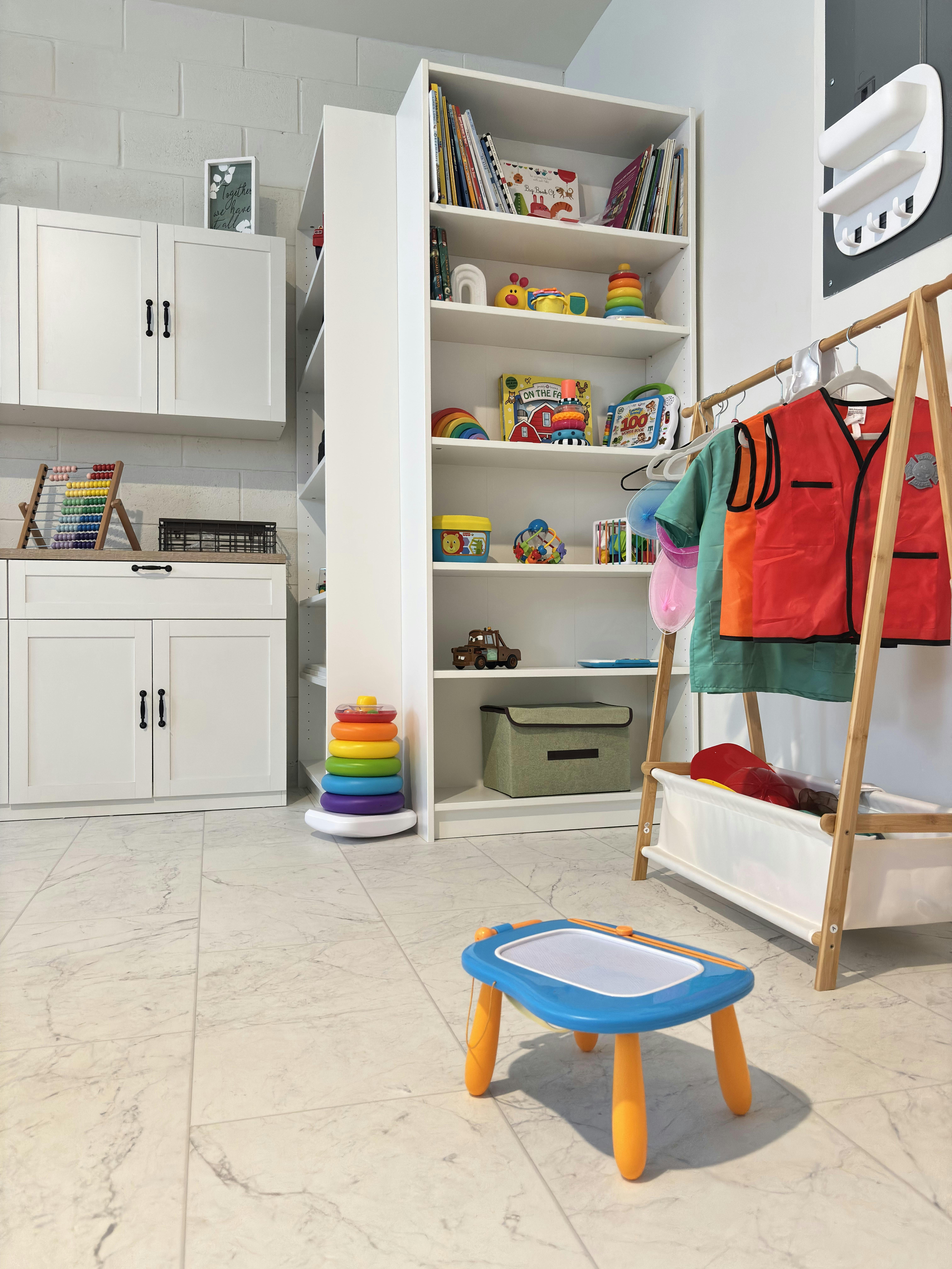 Playroom with shelves of toys, a clothing rack, and a child's drawing table