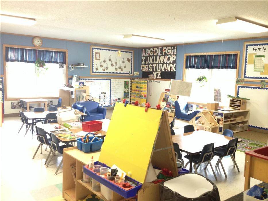 An empty classroom with tables, chairs, and learning materials