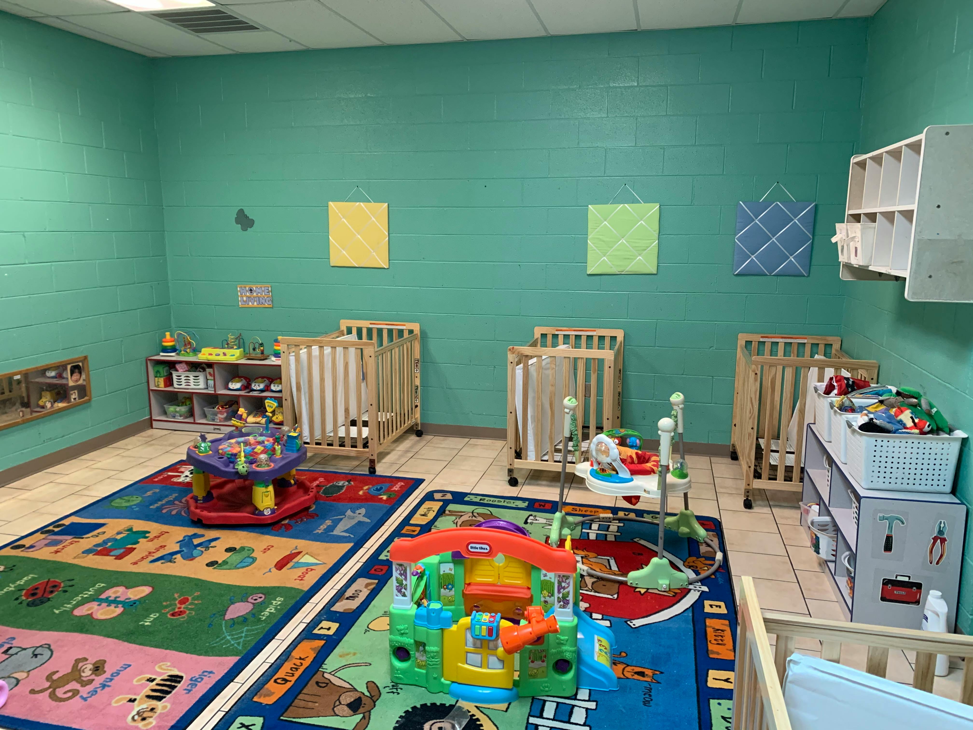 Cribs and colorful toys on patterned rugs in a childcare room