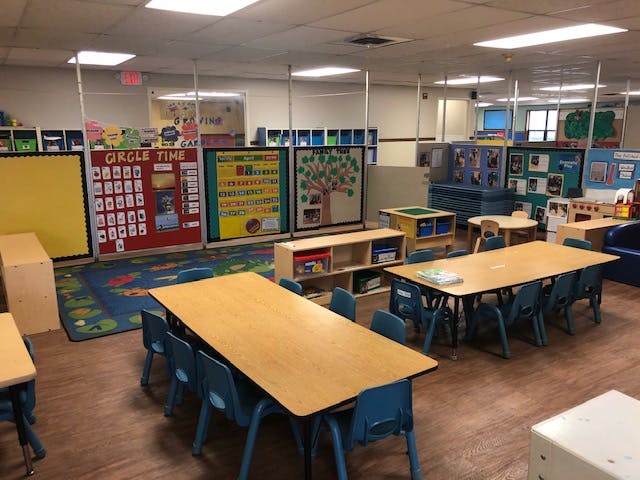 Classroom with small tables and chairs, activity boards, and play areas