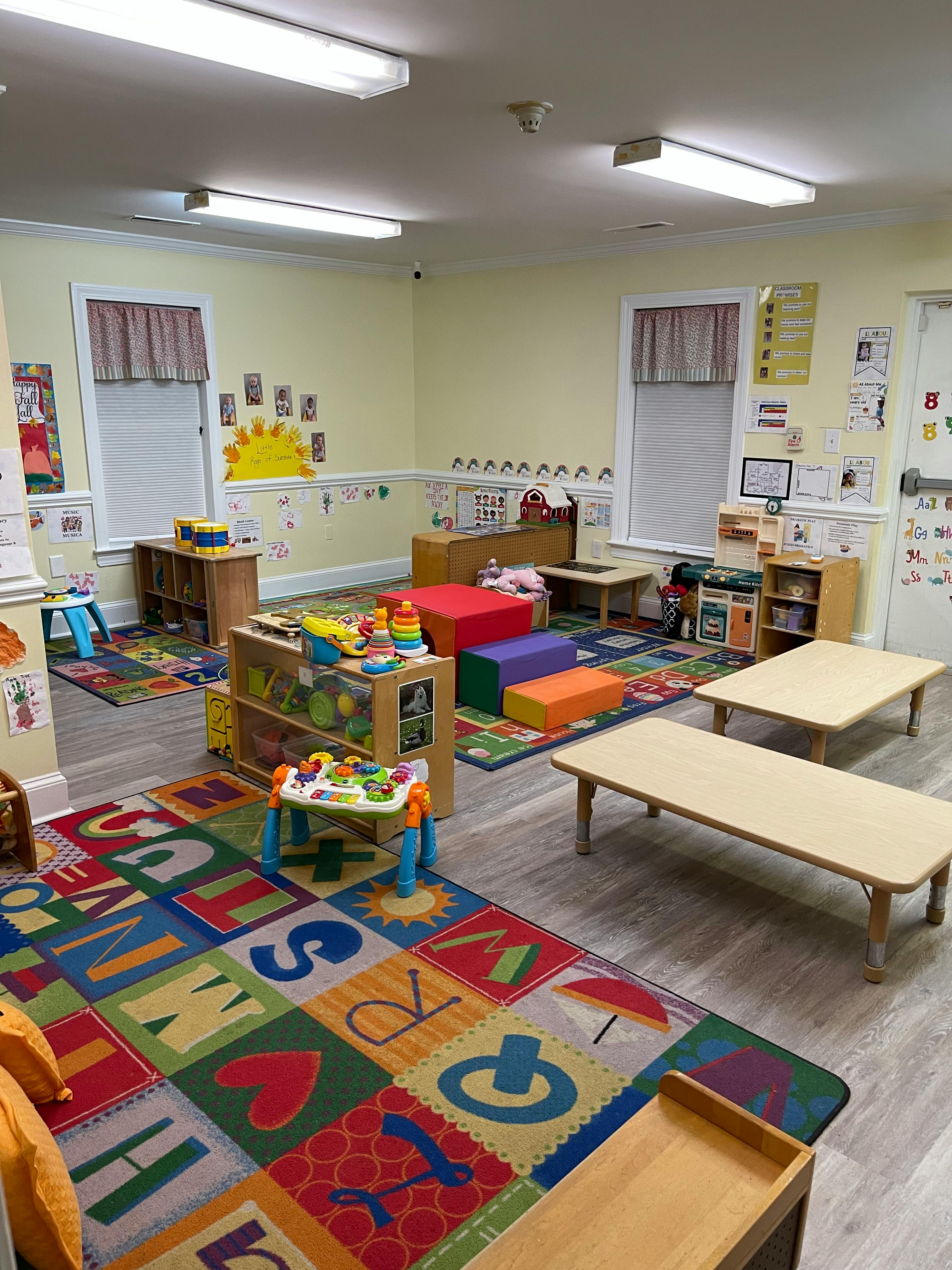 A classroom with small tables, chairs, and colorful rugs
