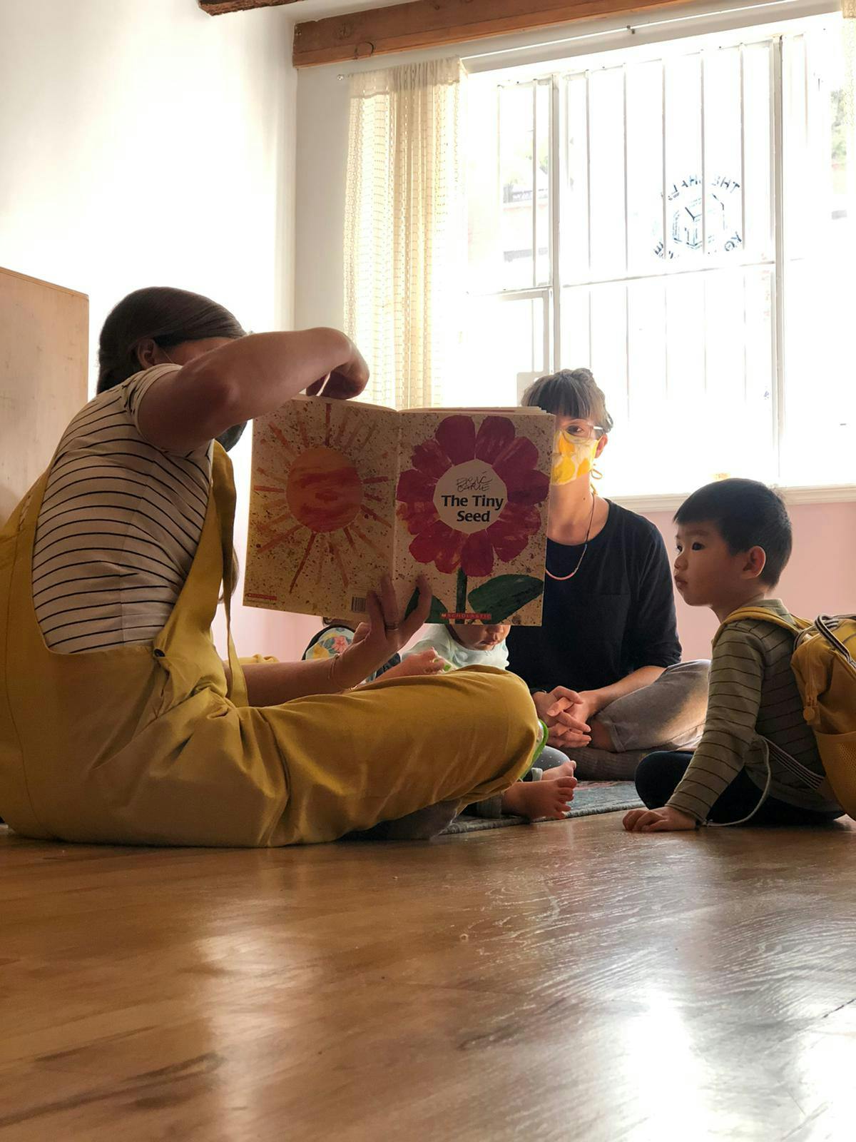 Person reading a book to two children in a classroom