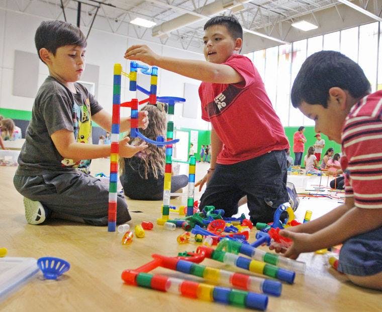 Three children playing with colorful building blocks on the floor