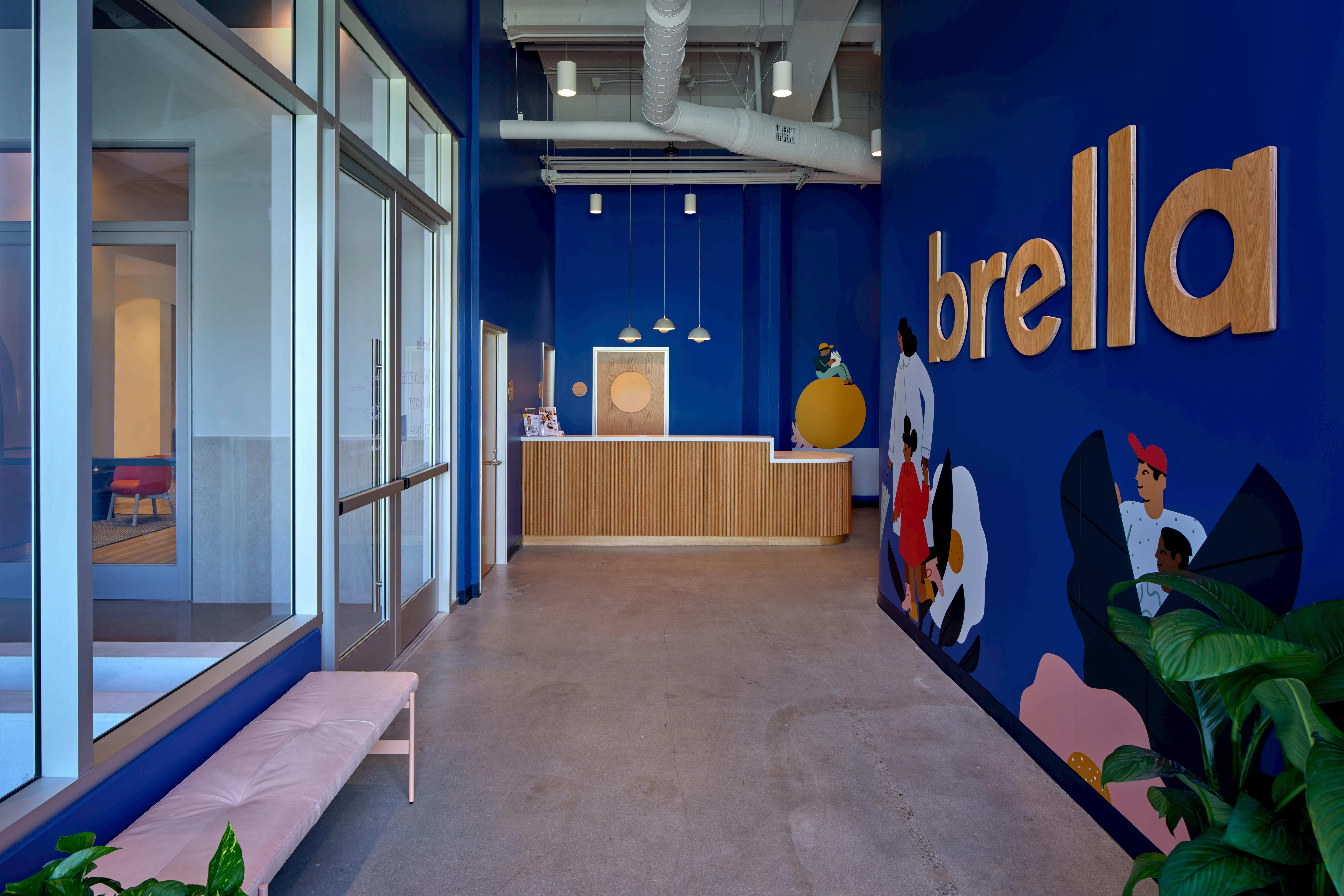 Lobby with a wooden reception desk and a blue wall with "brella" text