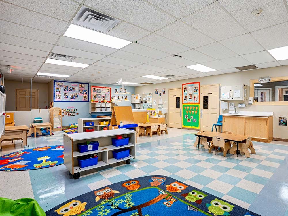 Empty classroom with small tables, chairs, and colorful rugs