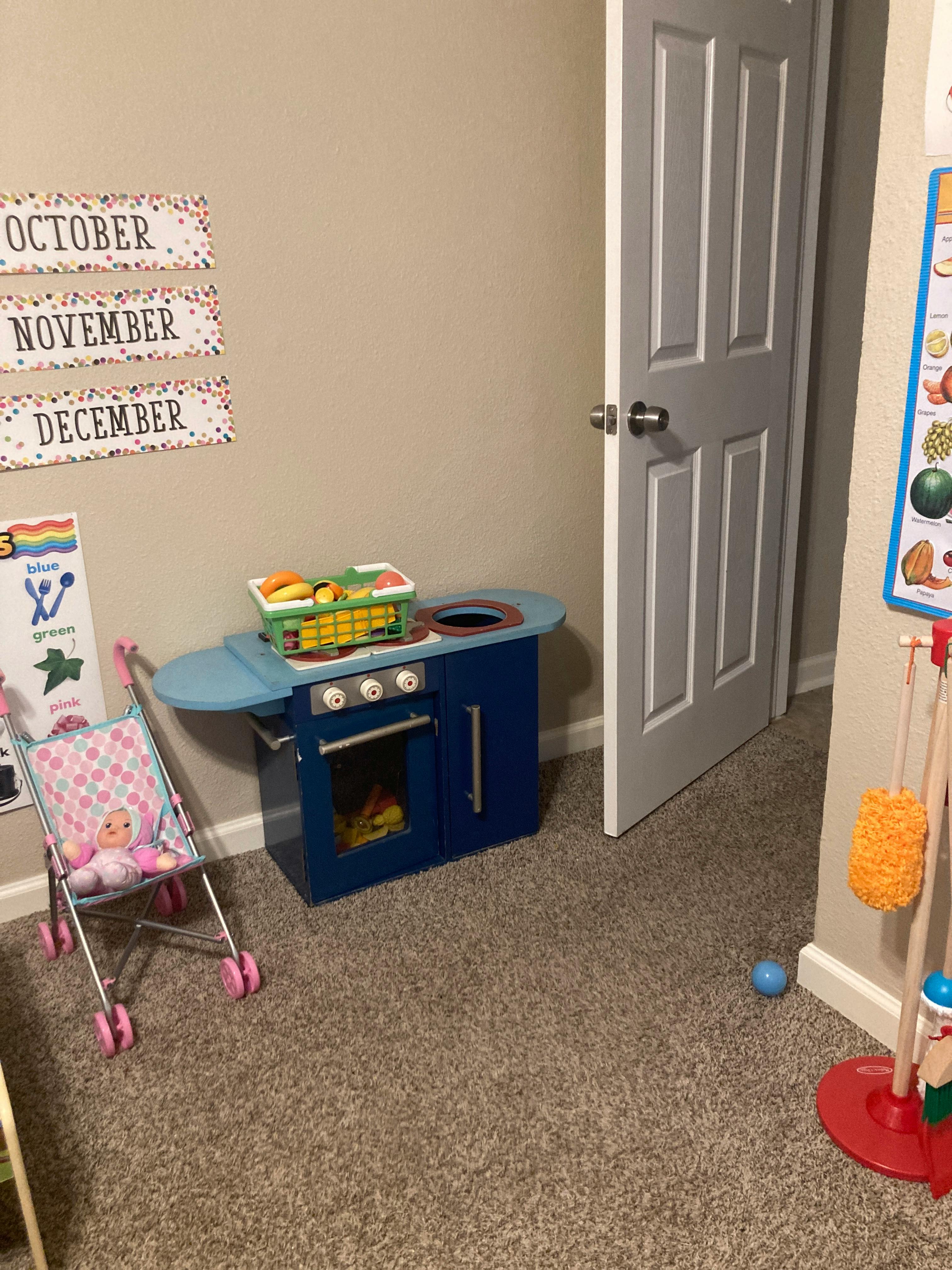 Child's play kitchen and doll stroller with a doll