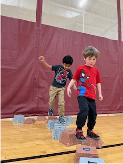 Two children walking on blocks in a gym