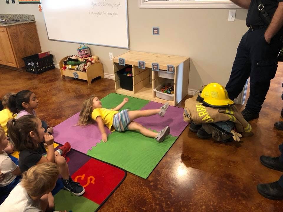 Child lying on a mat with other children watching