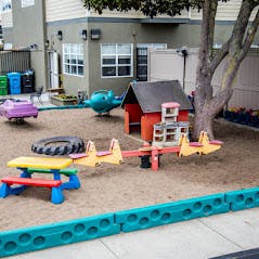 Outdoor play area with sandbox, seesaw, and small playhouse
