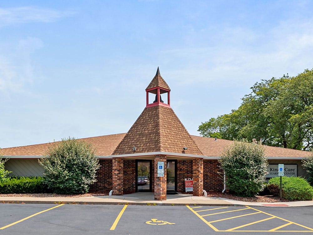 Brick building with a brown shingled roof and a bell tower entrance