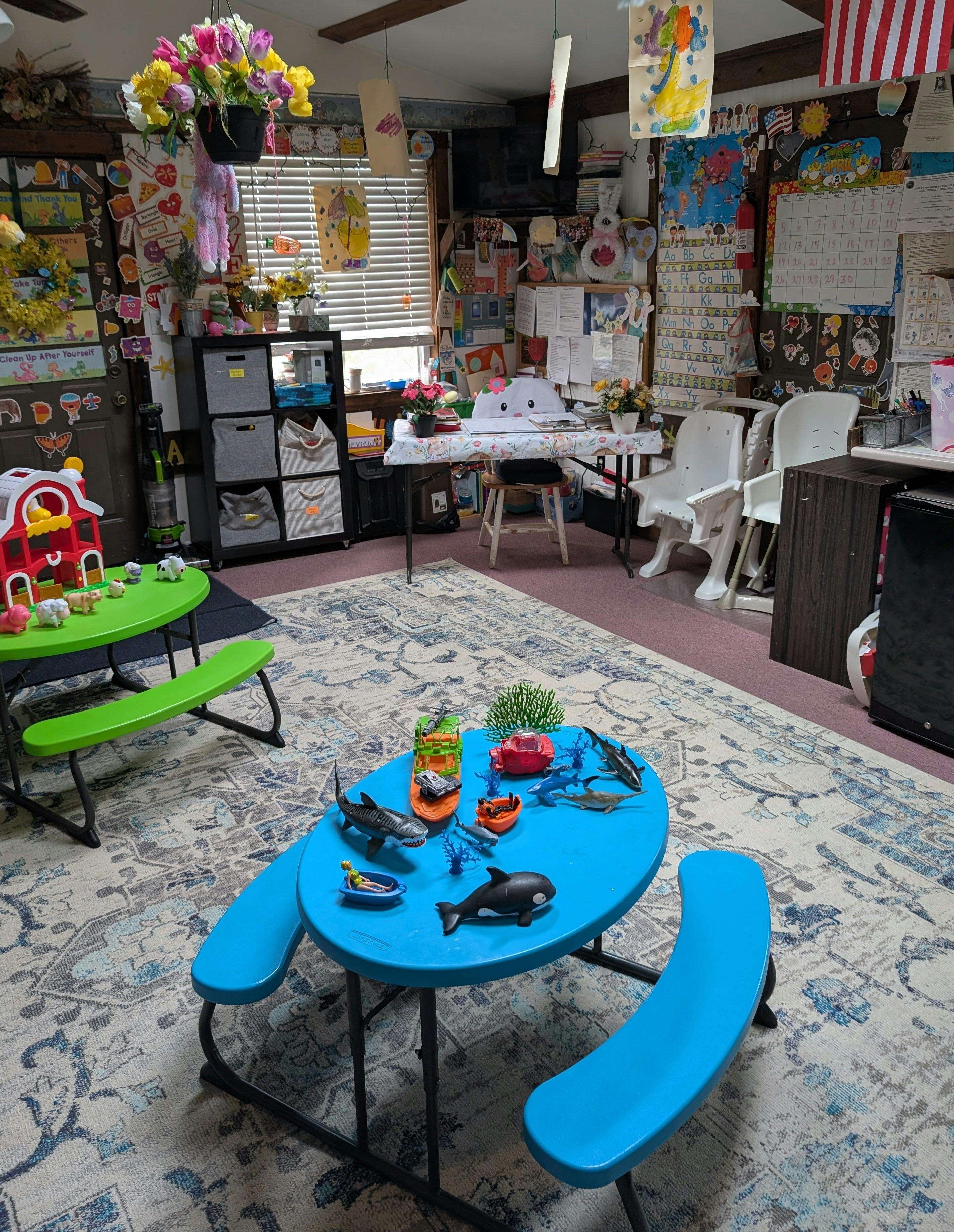 A classroom with small green and blue tables, toys, and decorations