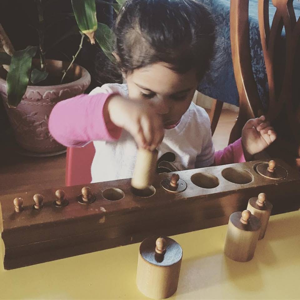 Child playing with a wooden cylinder block puzzle