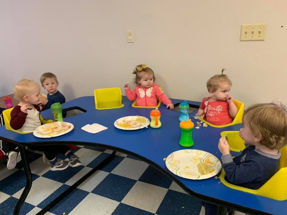 Children sitting at a blue table with plates of food