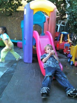 Child on a pink slide, another child in background