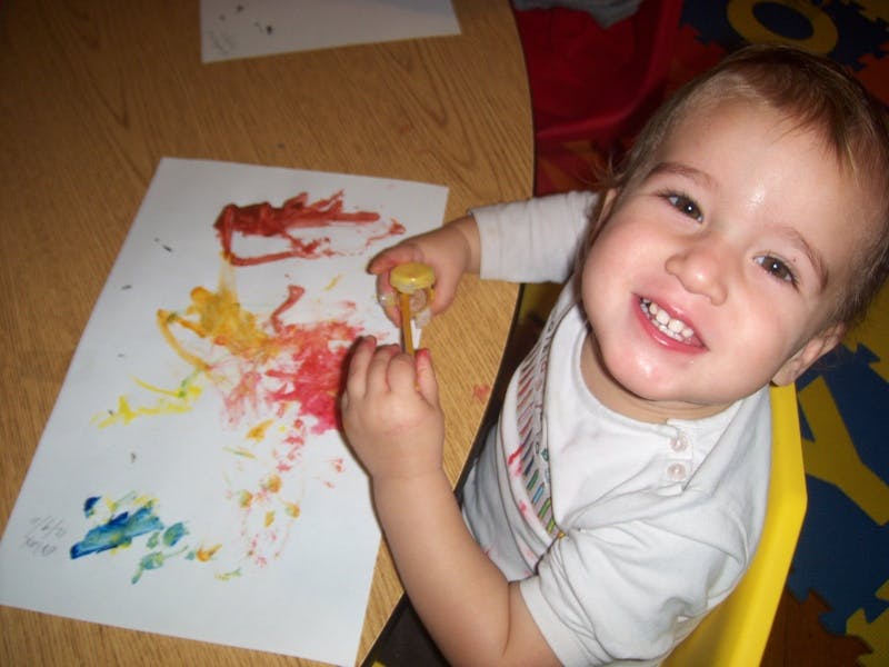 Child painting on paper with colorful paint