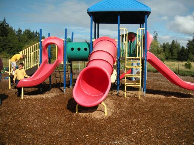 Child standing on a playground structure with slides