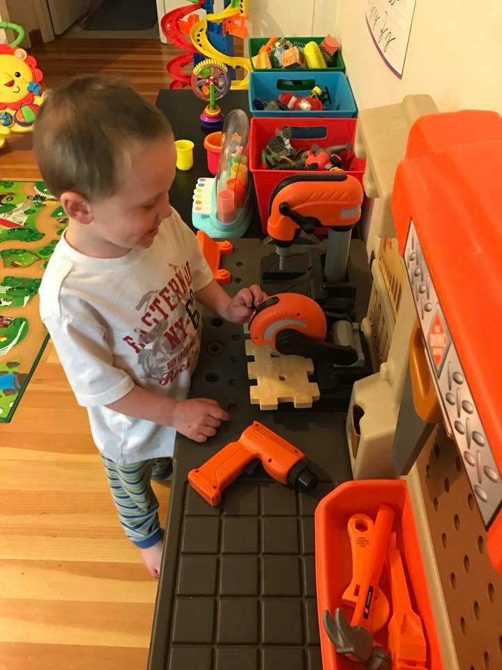 Child playing with toy tools at a workbench