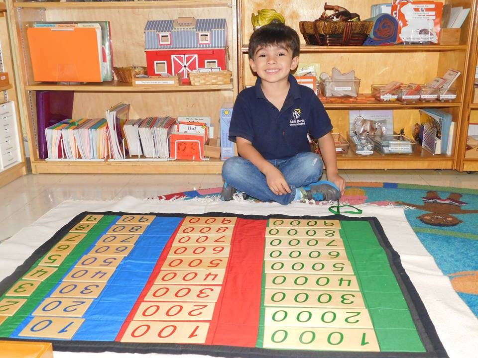 Child sitting on floor with a large number mat