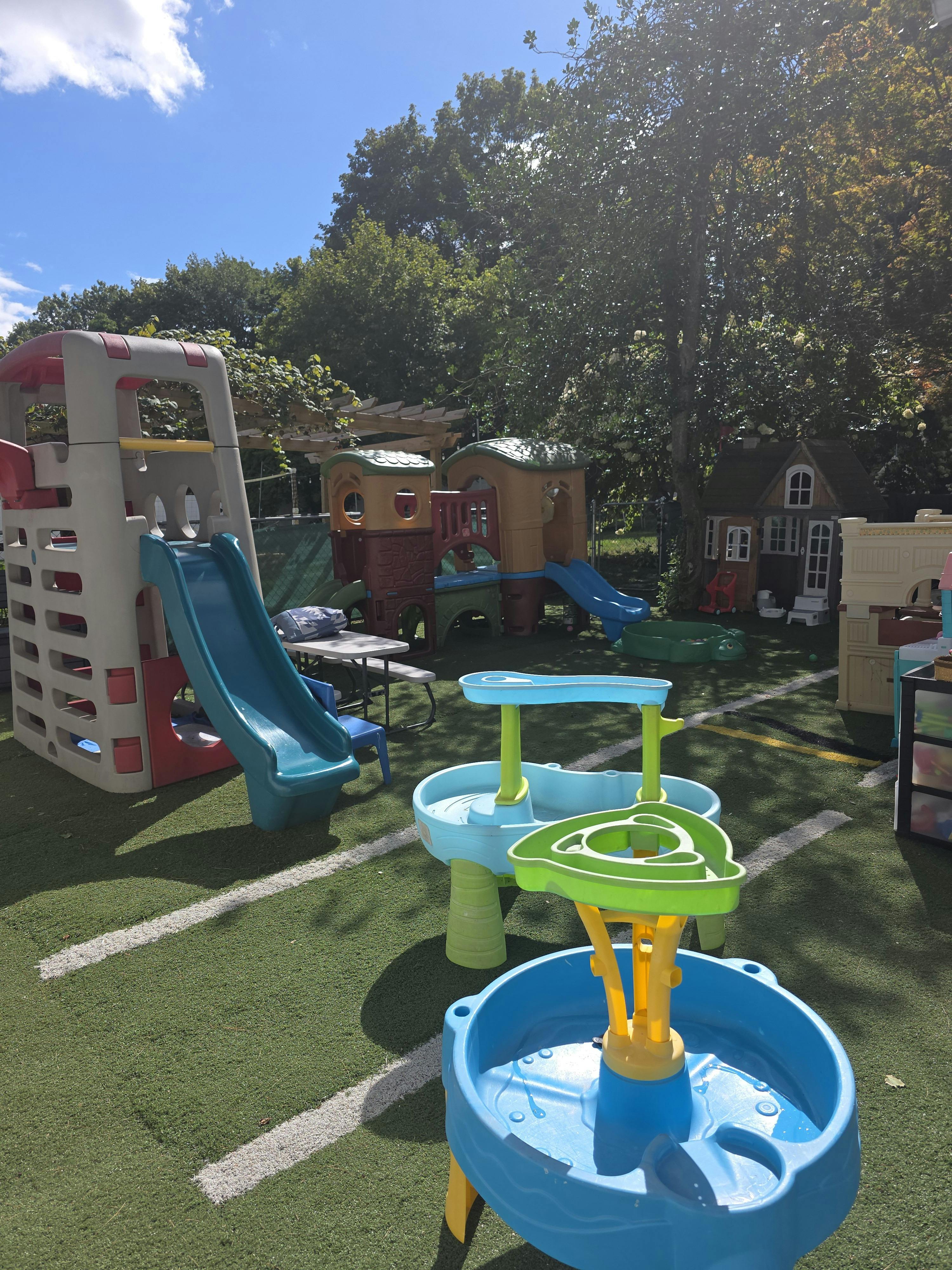Outdoor playground with slides, playhouses, and water tables on artificial turf