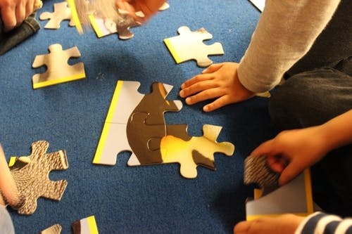 People assembling a jigsaw puzzle on a blue surface