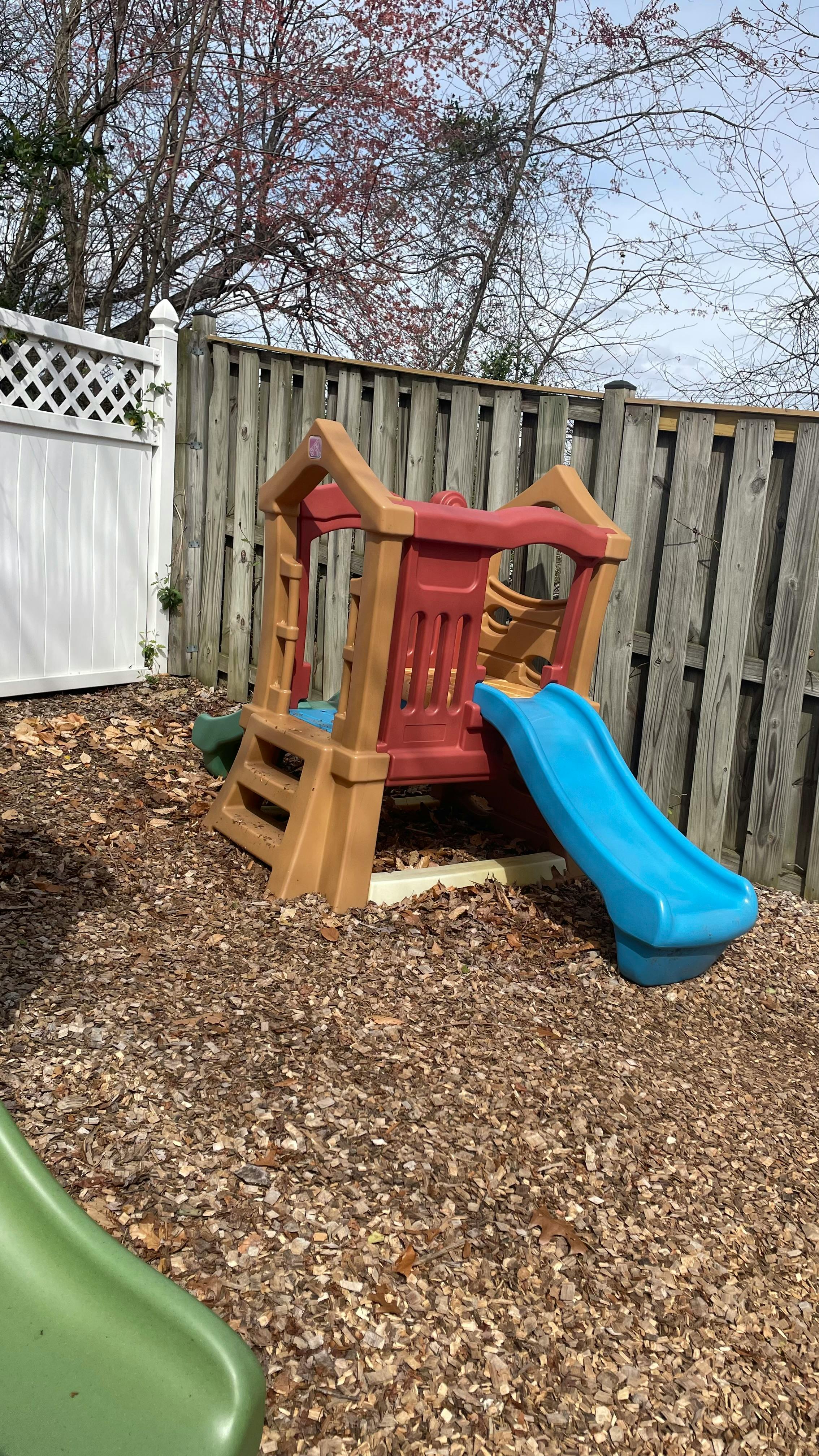 Playground structure with a blue slide on wood chips