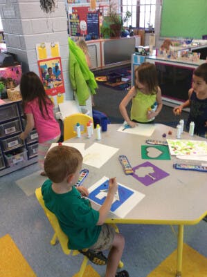 Children doing crafts at a table in a classroom