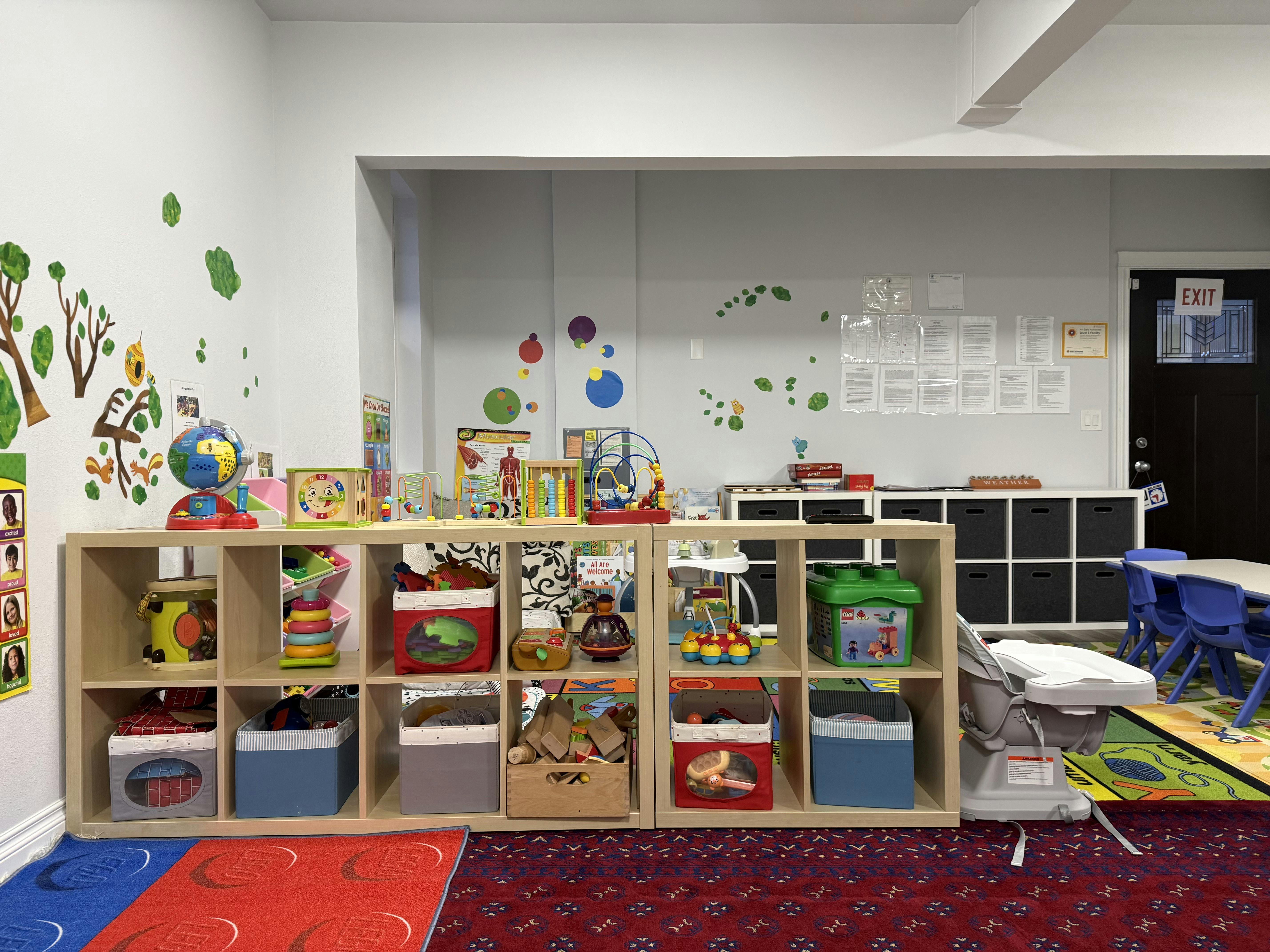 Classroom with shelves of toys, learning posters, and children's tables and chairs