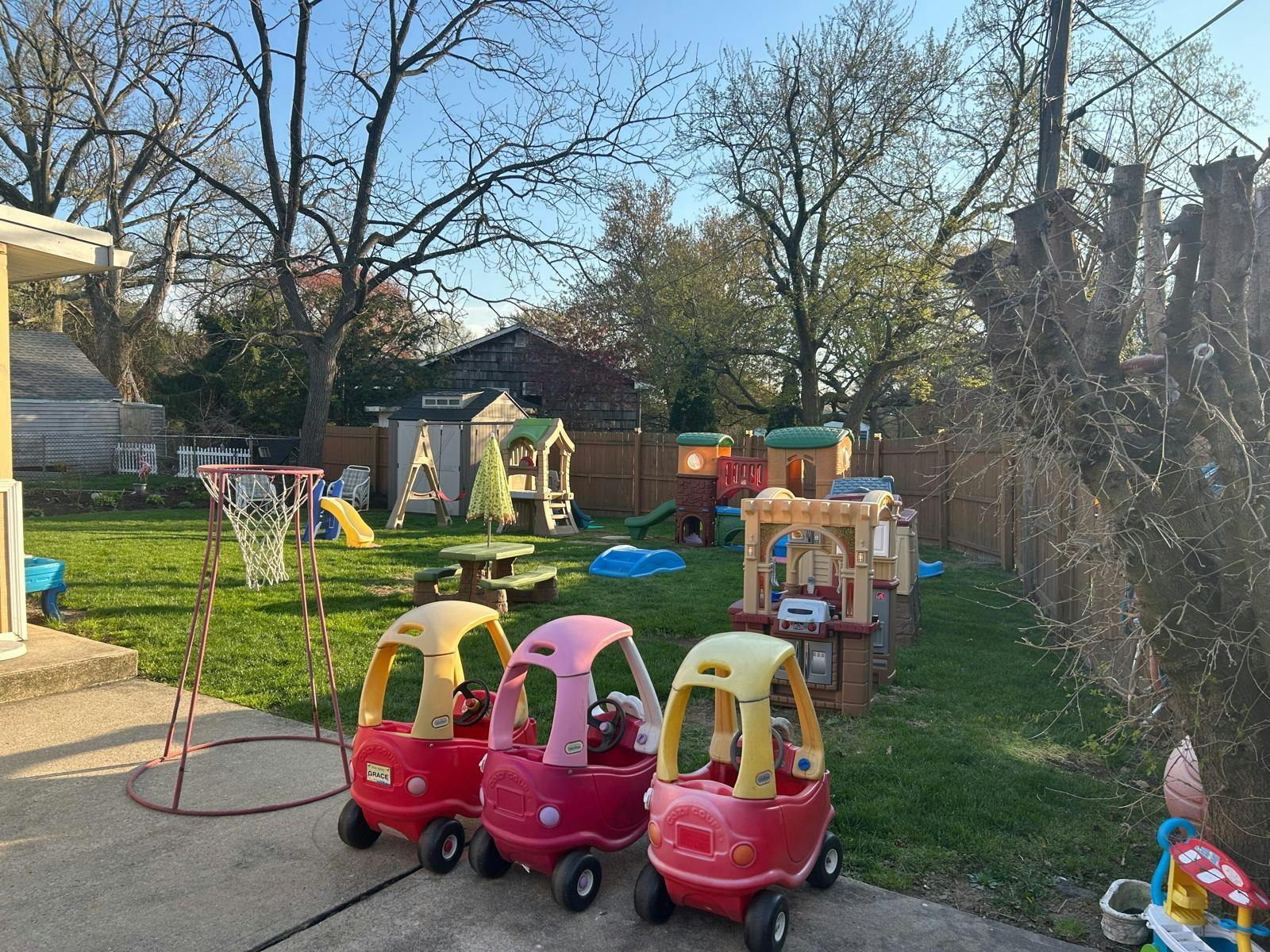 Plastic toy cars and playground equipment in a backyard