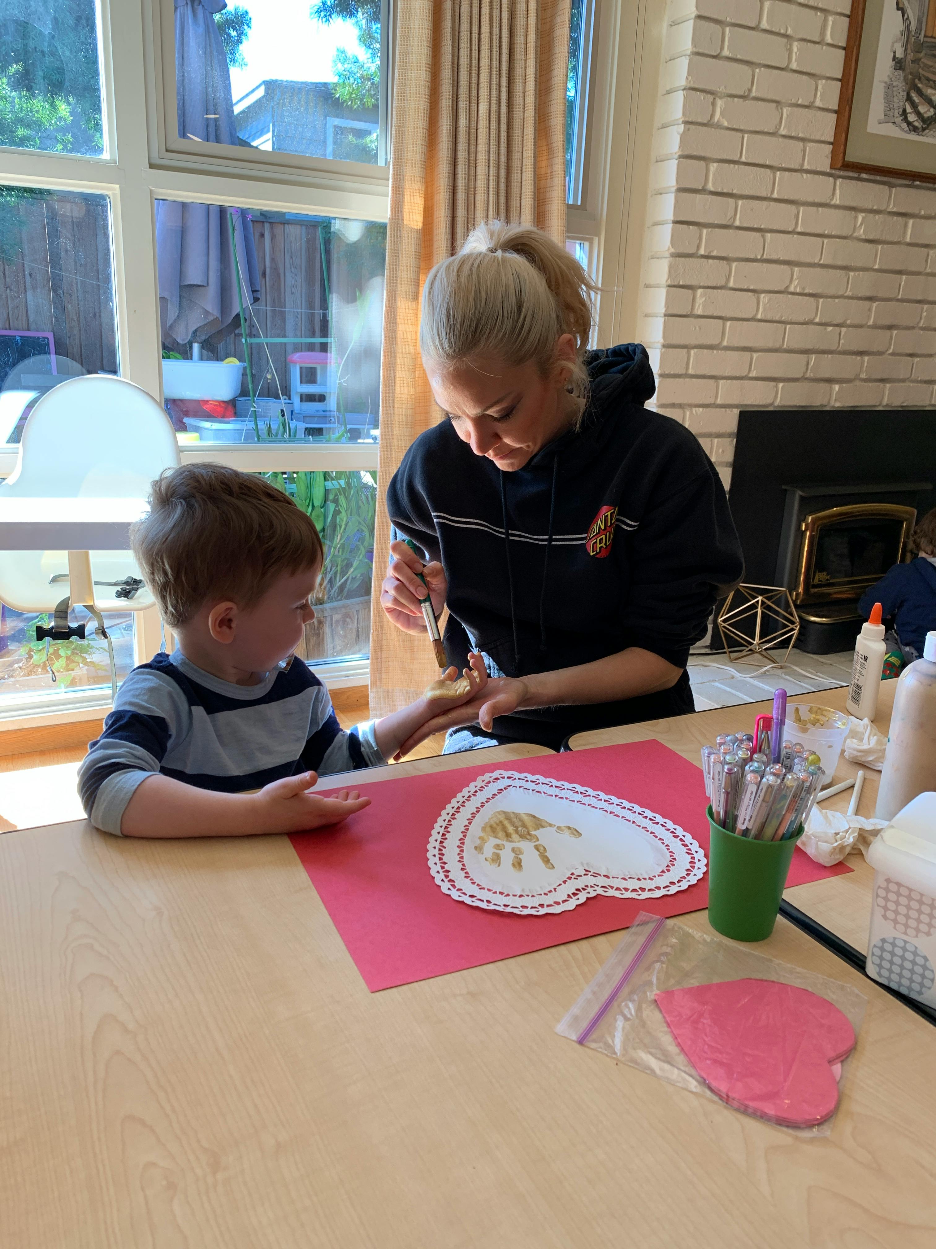 Person painting a child's hand at a table