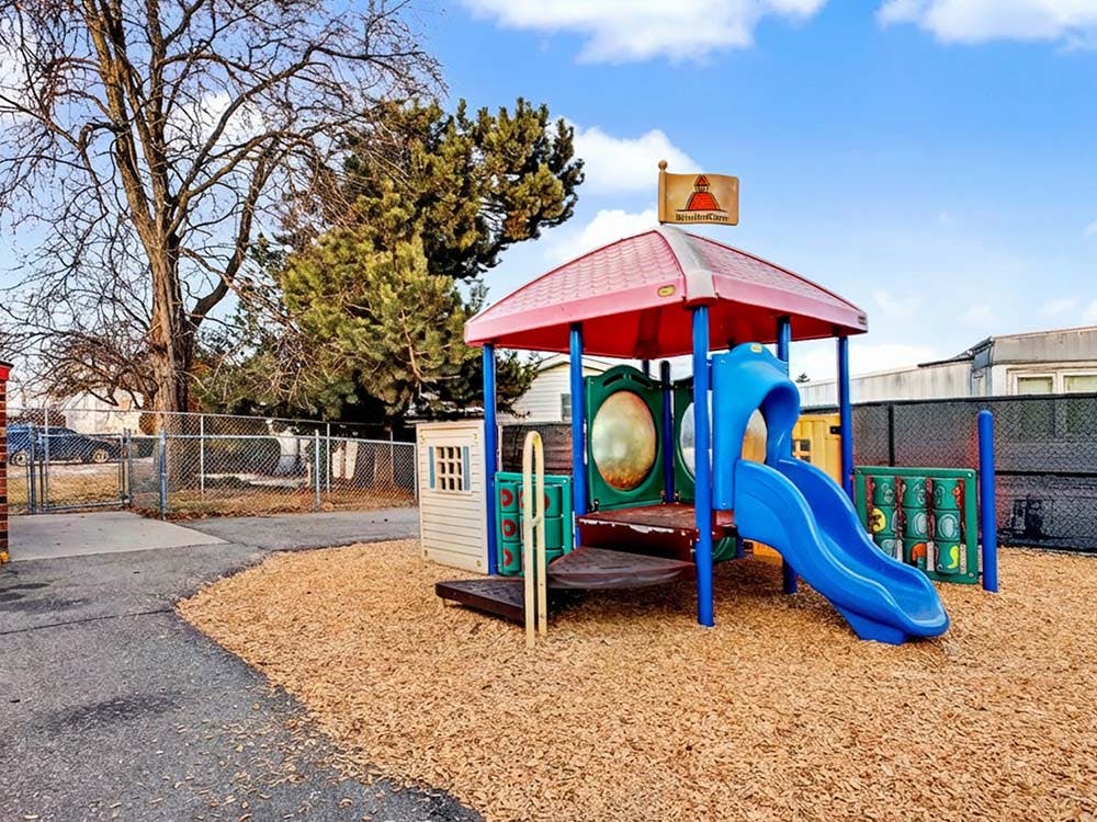 Playground with a blue slide, red roof, and wood chip ground cover