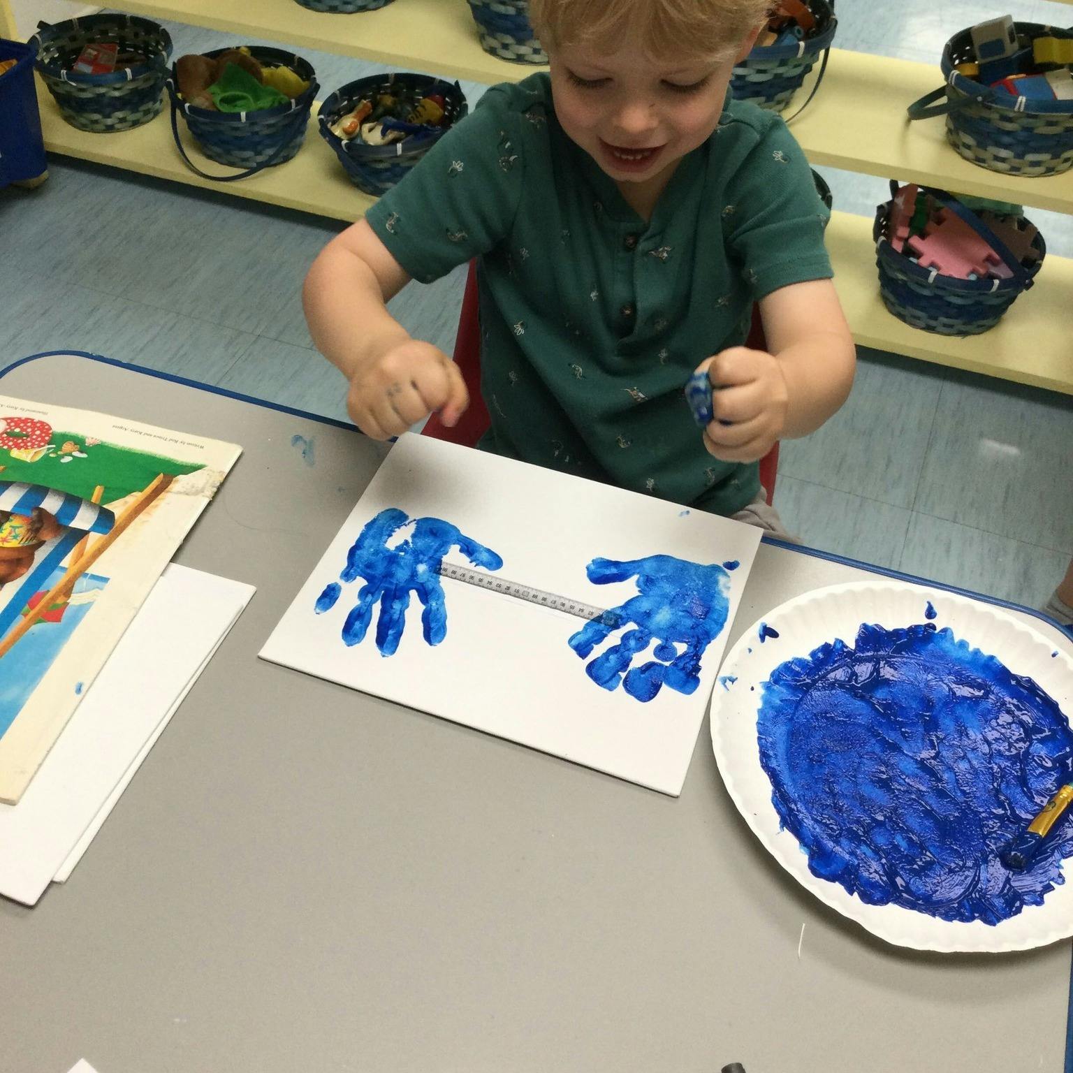 Child making blue handprints on paper