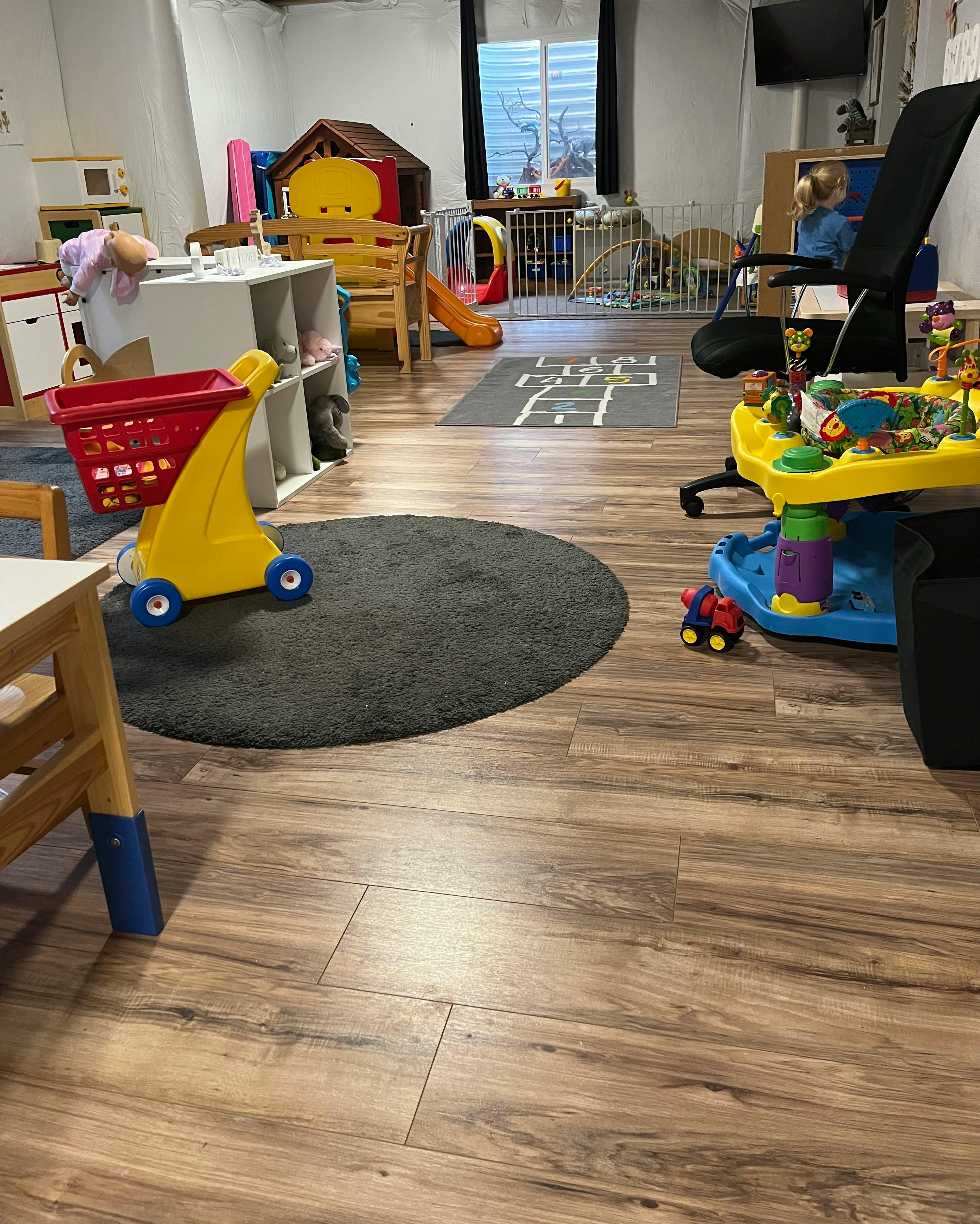 Playroom with various toys, including a yellow shopping cart and playhouse