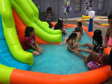 Children playing in an inflatable pool with a slide