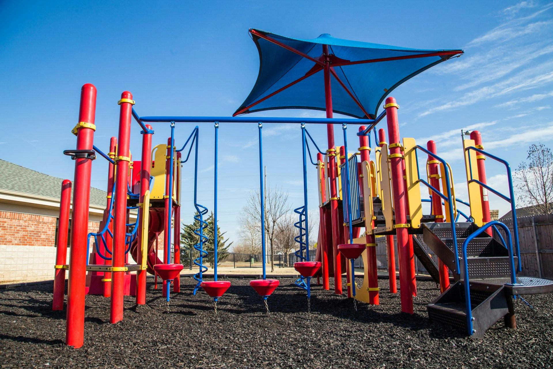 Empty playground with red, yellow, and blue equipment