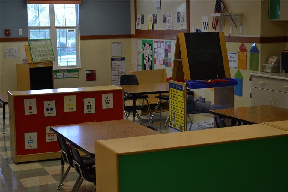Empty classroom with small tables, chairs, and learning aids