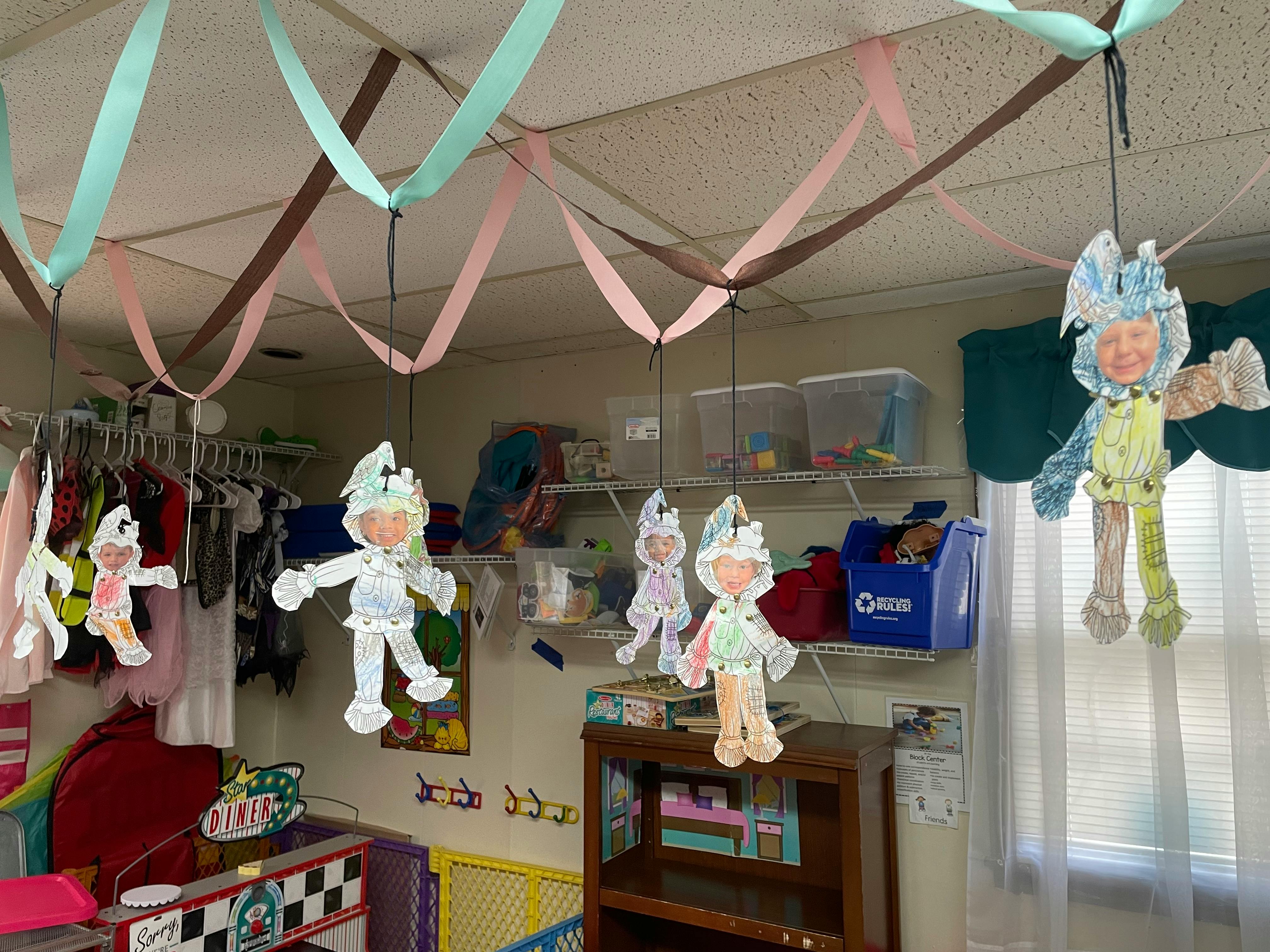 Paper cutouts of people hanging from the ceiling with streamers