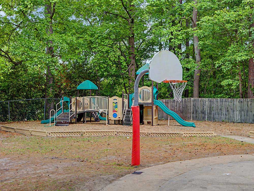 An outdoor playground with slides and swings, and a basketball hoop