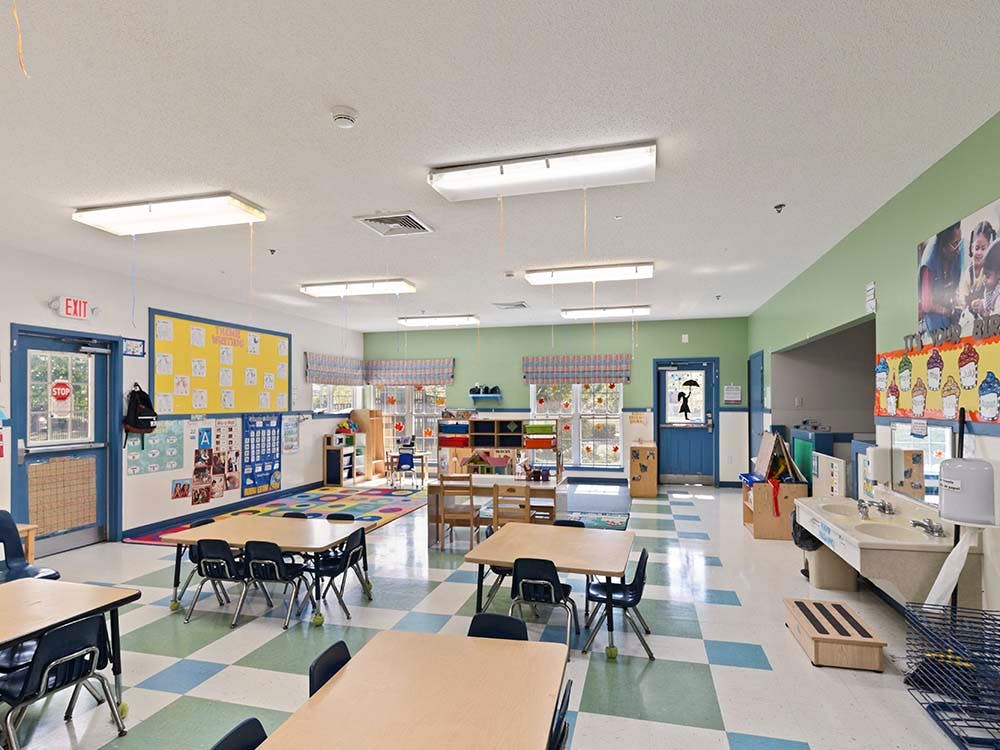 Classroom with small tables and chairs, colorful walls, and a sink area