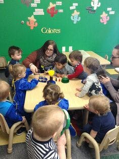 Adults and children gathered around a table in a classroom