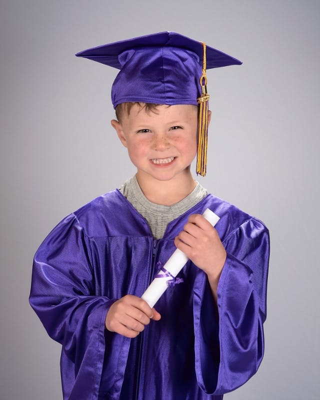 Child in a graduation cap and gown holding a diploma